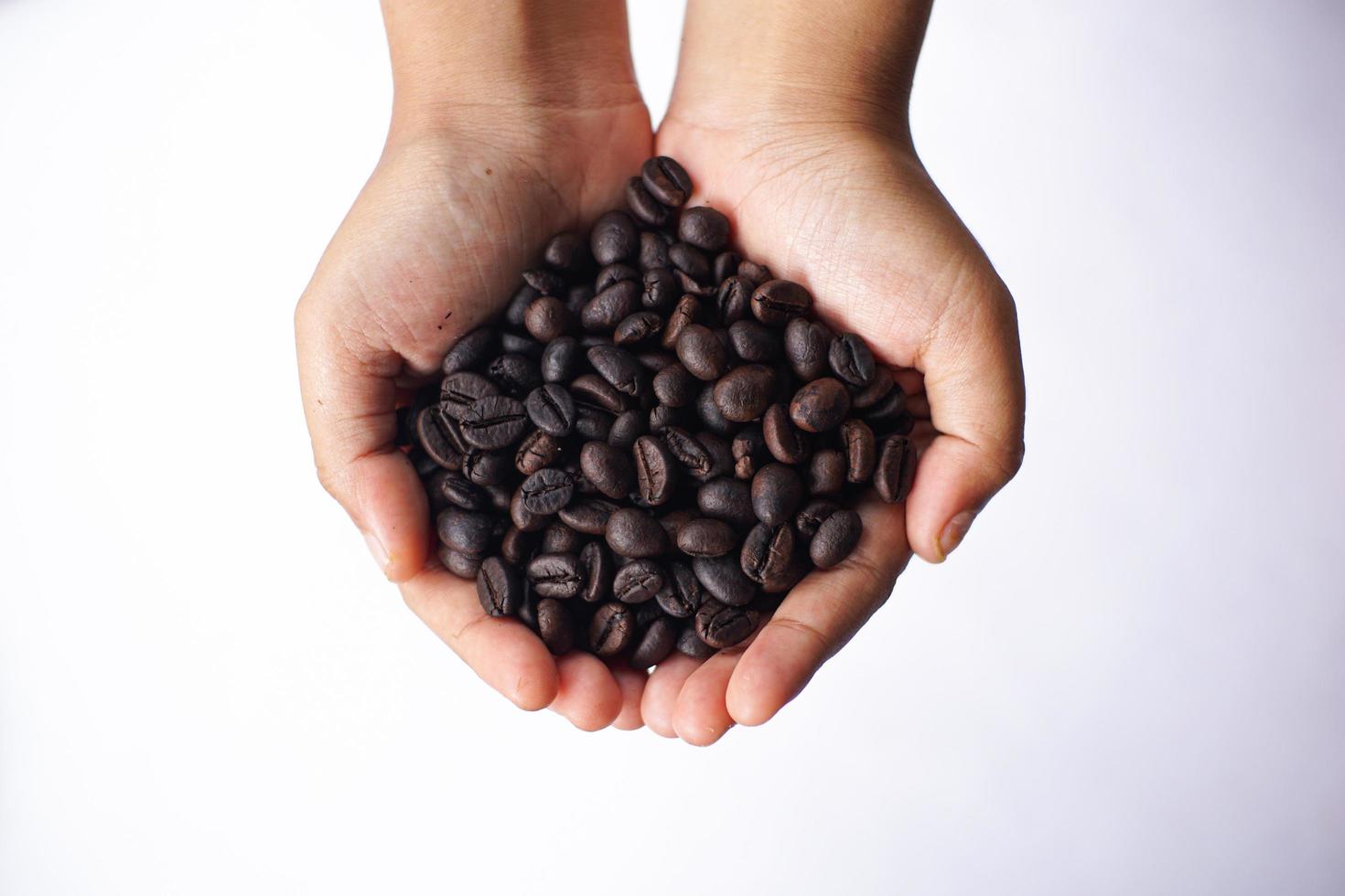 grãos de café na mão na mesa branca foto