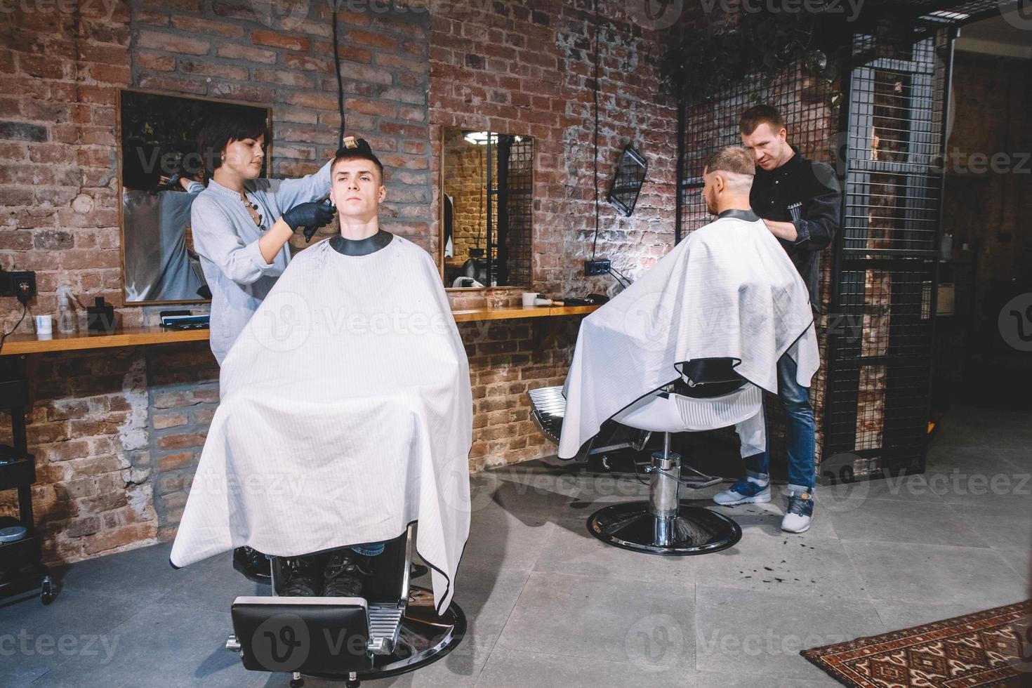 cabeleireiros cortam clientes na barbearia. conceito de publicidade e barbearia foto