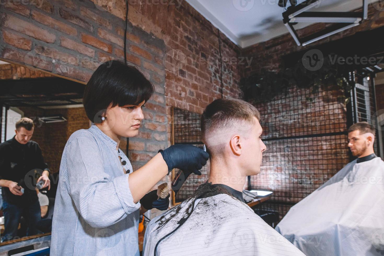 cabeleireiros cortam clientes na barbearia. conceito de publicidade e barbearia foto