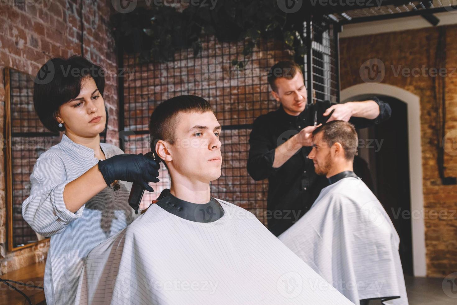 cabeleireiros cortam clientes na barbearia. conceito de publicidade e barbearia foto