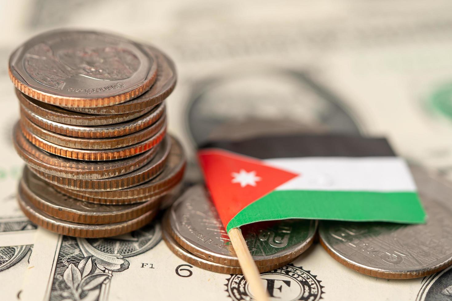 pilha de moedas com a bandeira da Jordânia em fundo de notas de dólar americano. foto