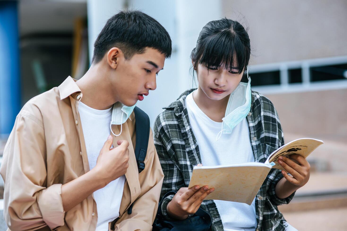 estudantes do sexo masculino e feminino sentados e lendo livros nas escadas. foto