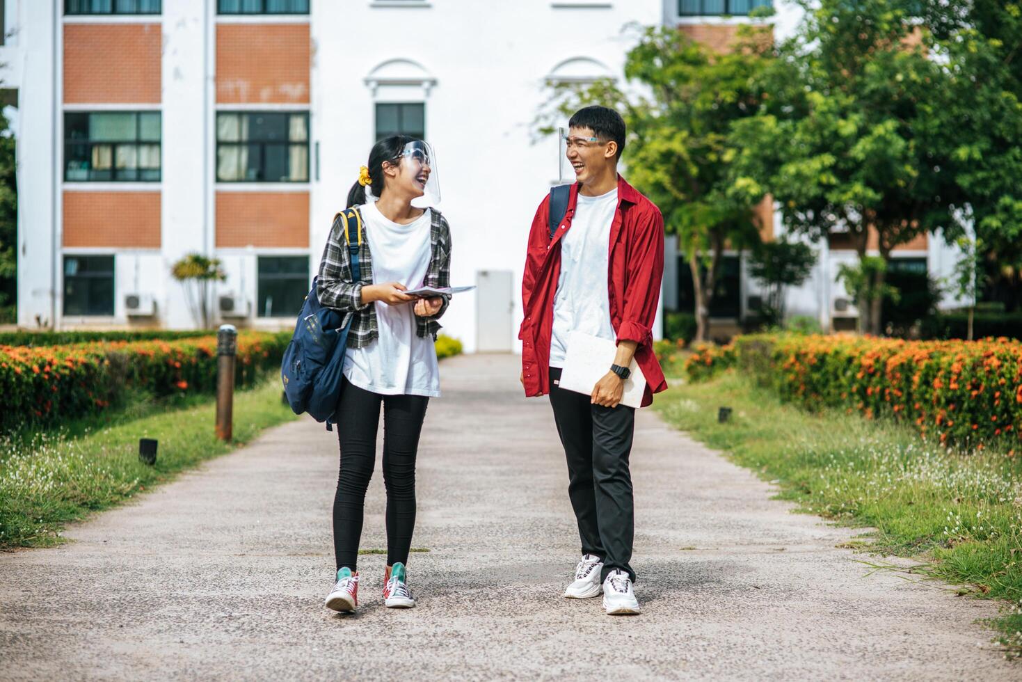 estudantes masculinos e femininos usam uma máscara facial e ficam em frente à universidade. foto