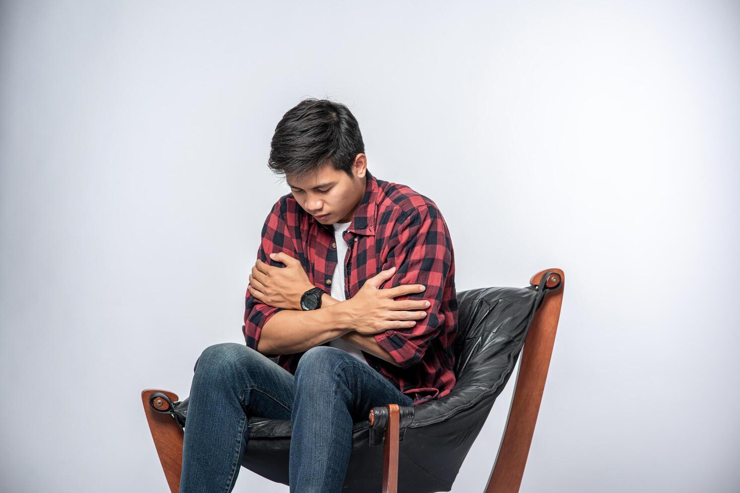 o homem de camisa listrada fica doente, senta-se em uma cadeira e cruza os braços. foto