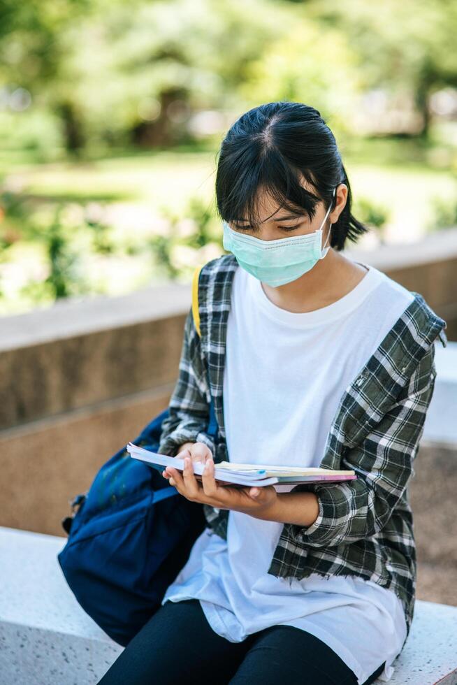 estudantes do sexo feminino usando máscaras e livros nas escadas. foto