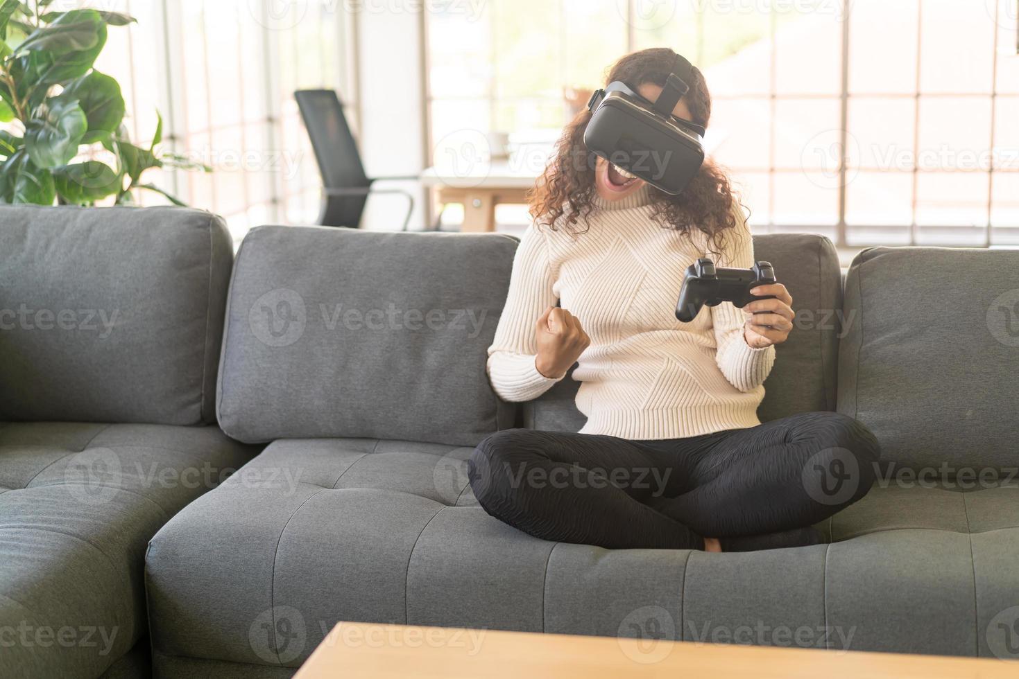 mulher latina usando um fone de ouvido de realidade virtual no sofá foto