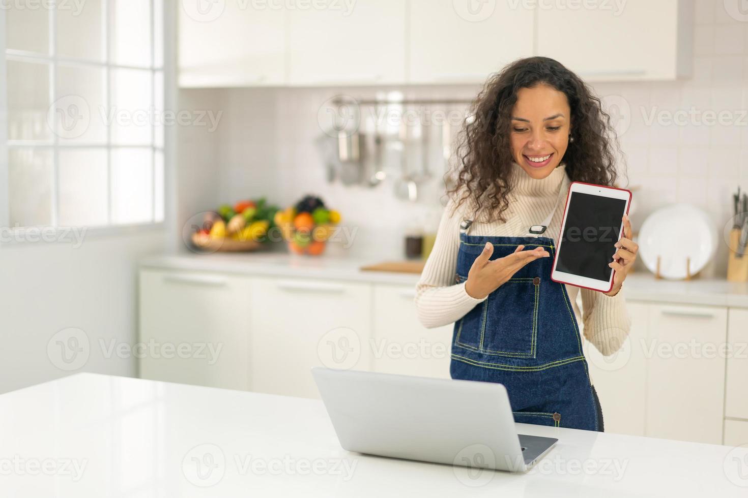 mulher latina gravando vídeo e cozinhando na cozinha foto