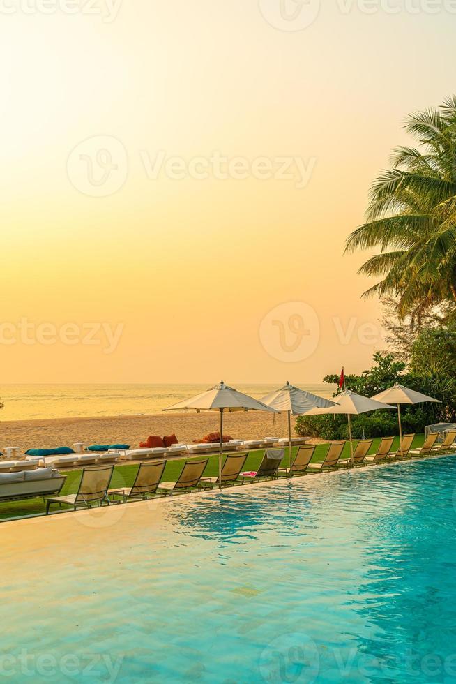 guarda-sol e cadeira ao redor da piscina com vista para o mar foto