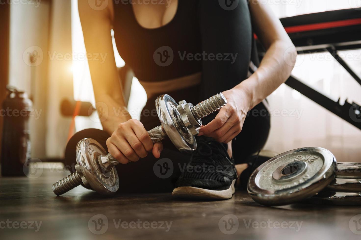 mulher determinada a perder peso em casa e a fazer exercício com halteres. conceito de esporte e recreação. mulher em roupas esportivas foto