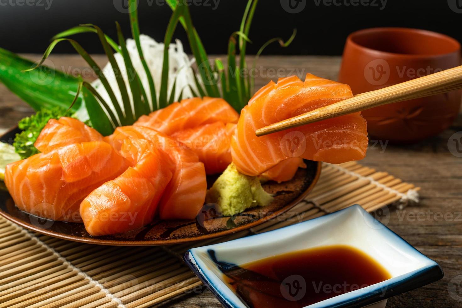 sashimi, salmão, pauzinhos de comida japonesa e wasabi na mesa de madeira foto