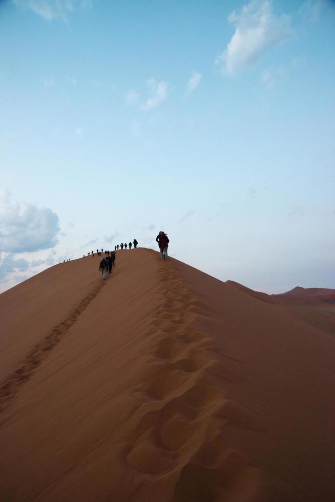 pessoas em uma fileira caminhando na duna 45 no deserto do namibe. namibia foto