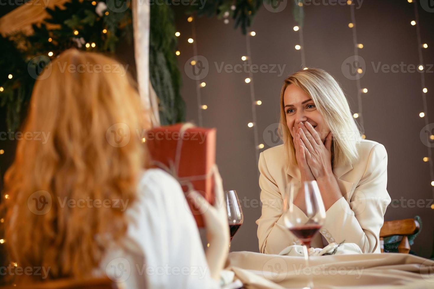 casal de lésbicas jantando em um restaurante. menina dando um presente para seu amor foto