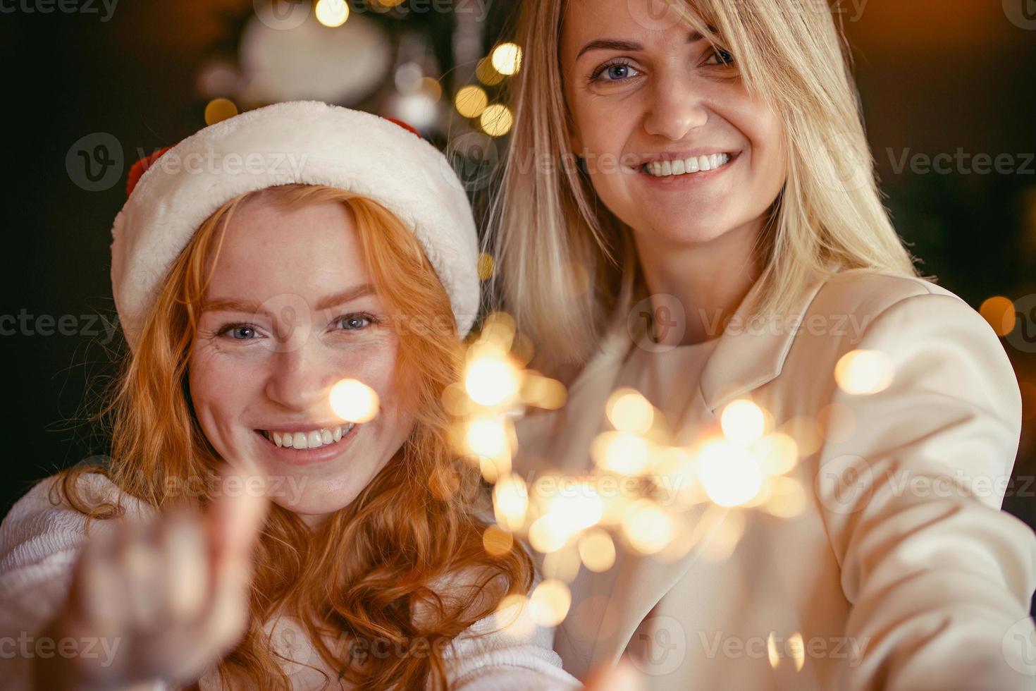 casal de lésbicas jantando para comemorar um feriado. meninas queimam fogos de artifício e sorriem para a câmera foto