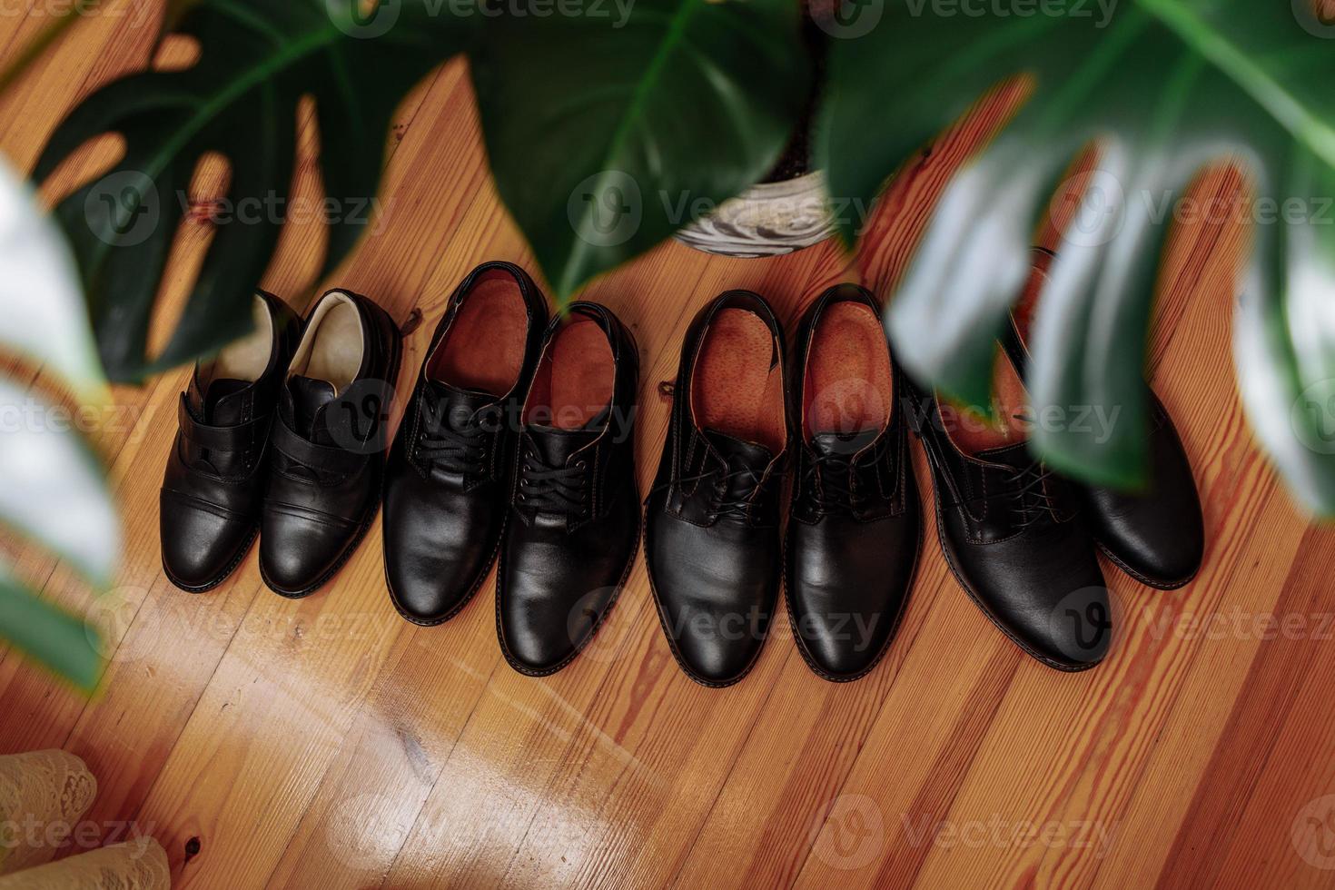 sapatos masculinos conceitos sapatos de couro preto colocados no chão perto da planta de casa. quatro pares de botas masculinas foto