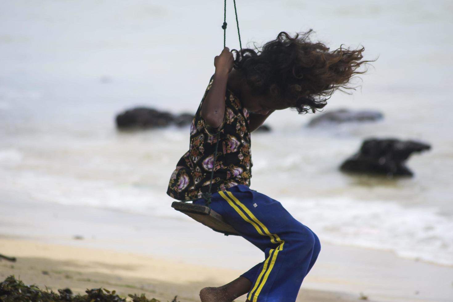 Sorong, West Papua, Indonésia, 12 de dezembro de 2021. uma jovem jogando swing na beira da praia foto