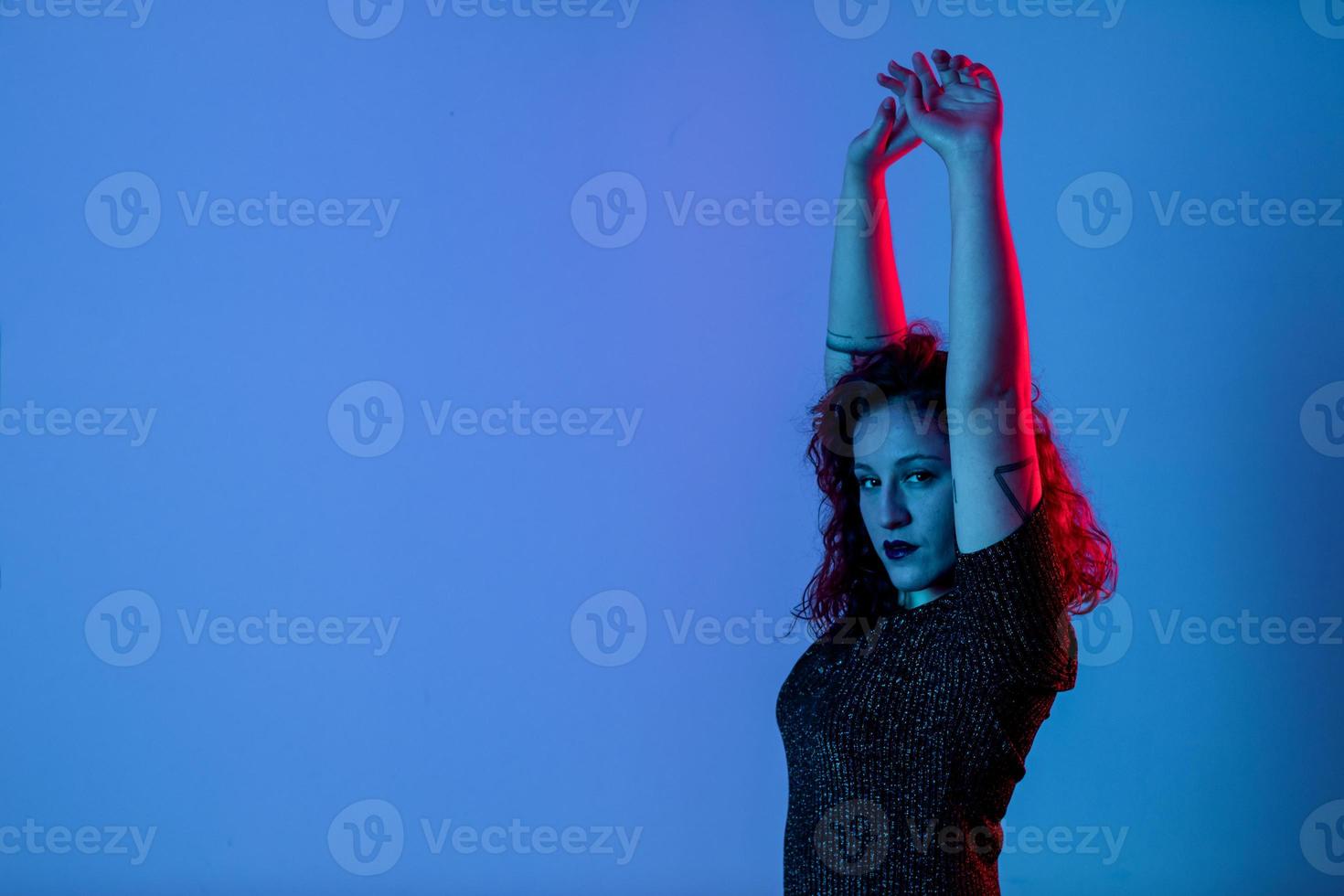retrato emocional, uma menina com as mãos para cima. luz de cor, azul e vermelho. tiro do estúdio. copyspace para inserir texto foto