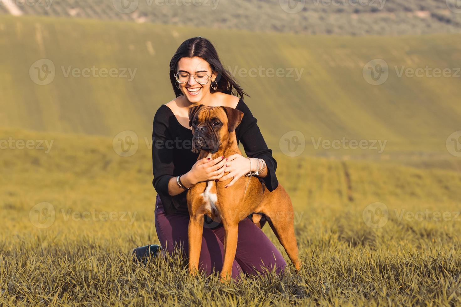 garota fashion com seu cachorro boxer no prado no outono foto