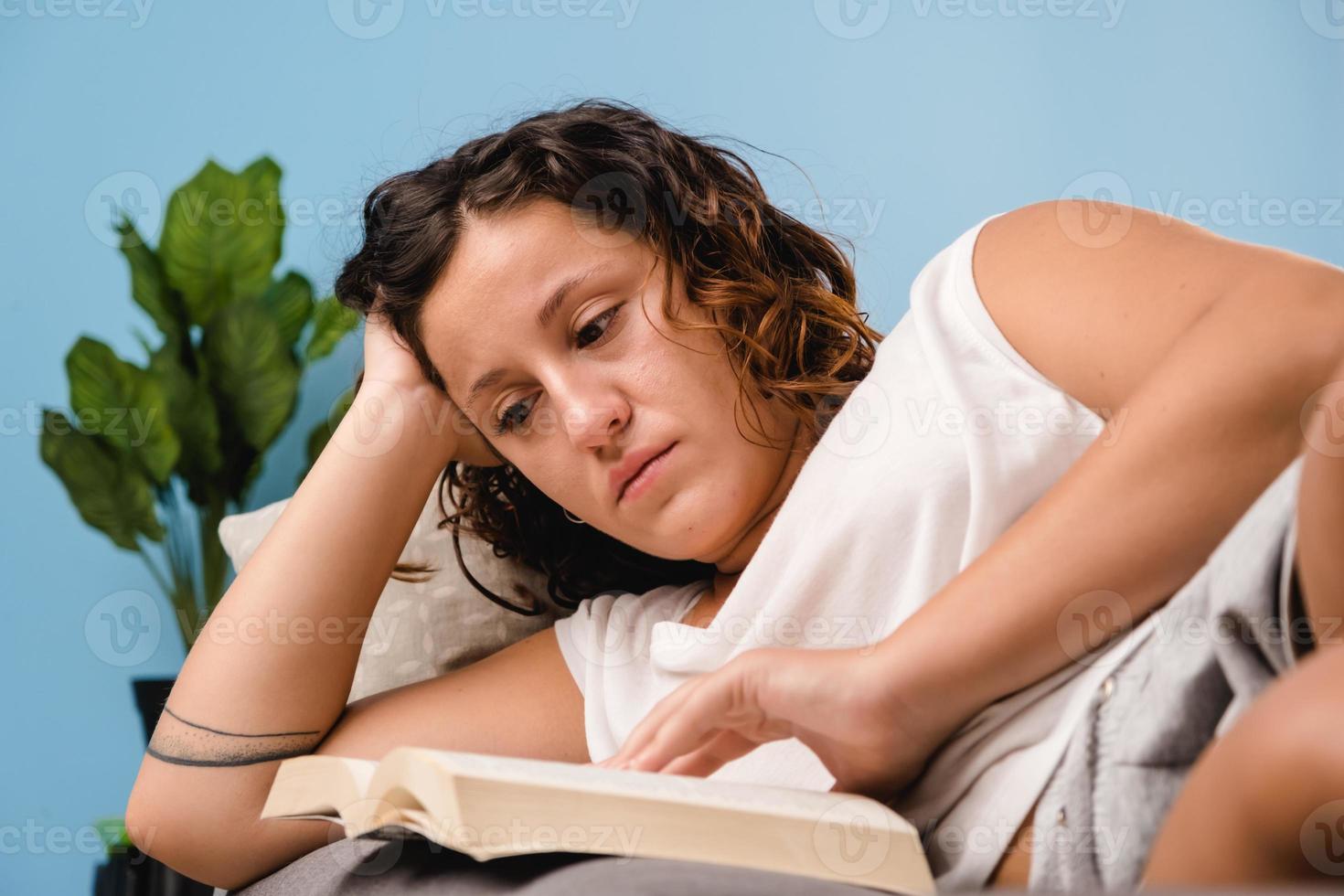 mulher lendo um livro na sala de estar sentada no sofá foto