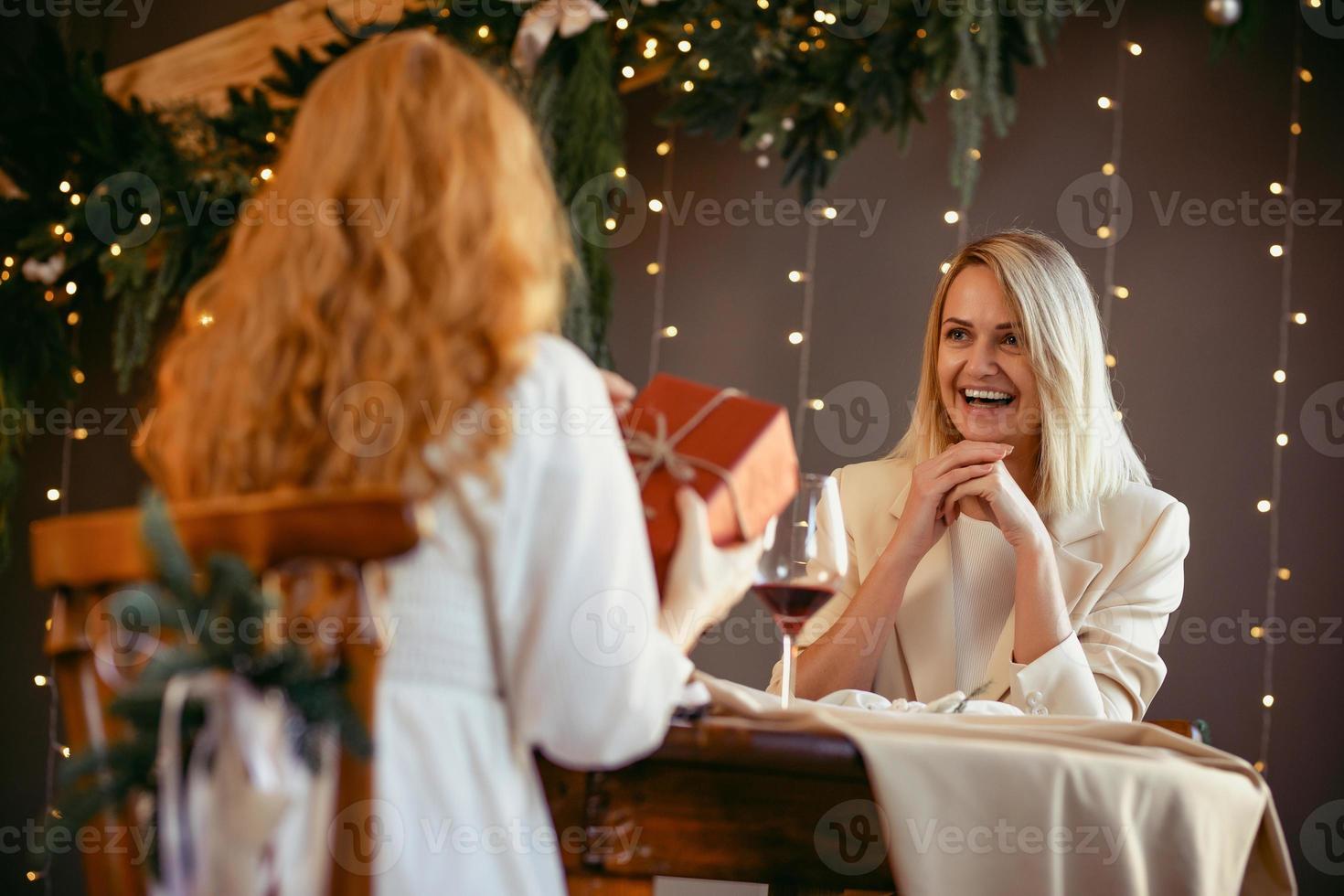 casal de lésbicas jantando em um restaurante. menina dando um presente para seu amor foto