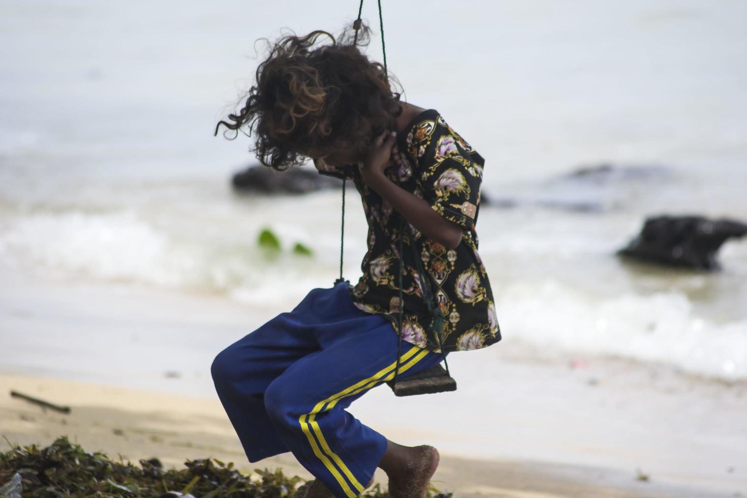 Sorong, West Papua, Indonésia, 12 de dezembro de 2021. uma jovem jogando swing na beira da praia foto