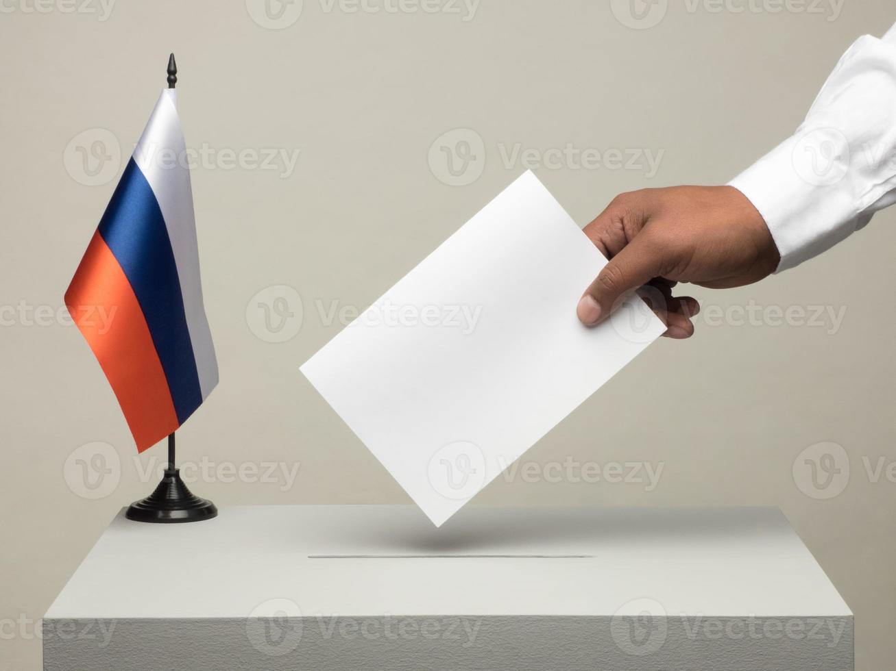urna com a bandeira nacional da Rússia. eleição presidencial em 2018. mão lançando uma cédula foto