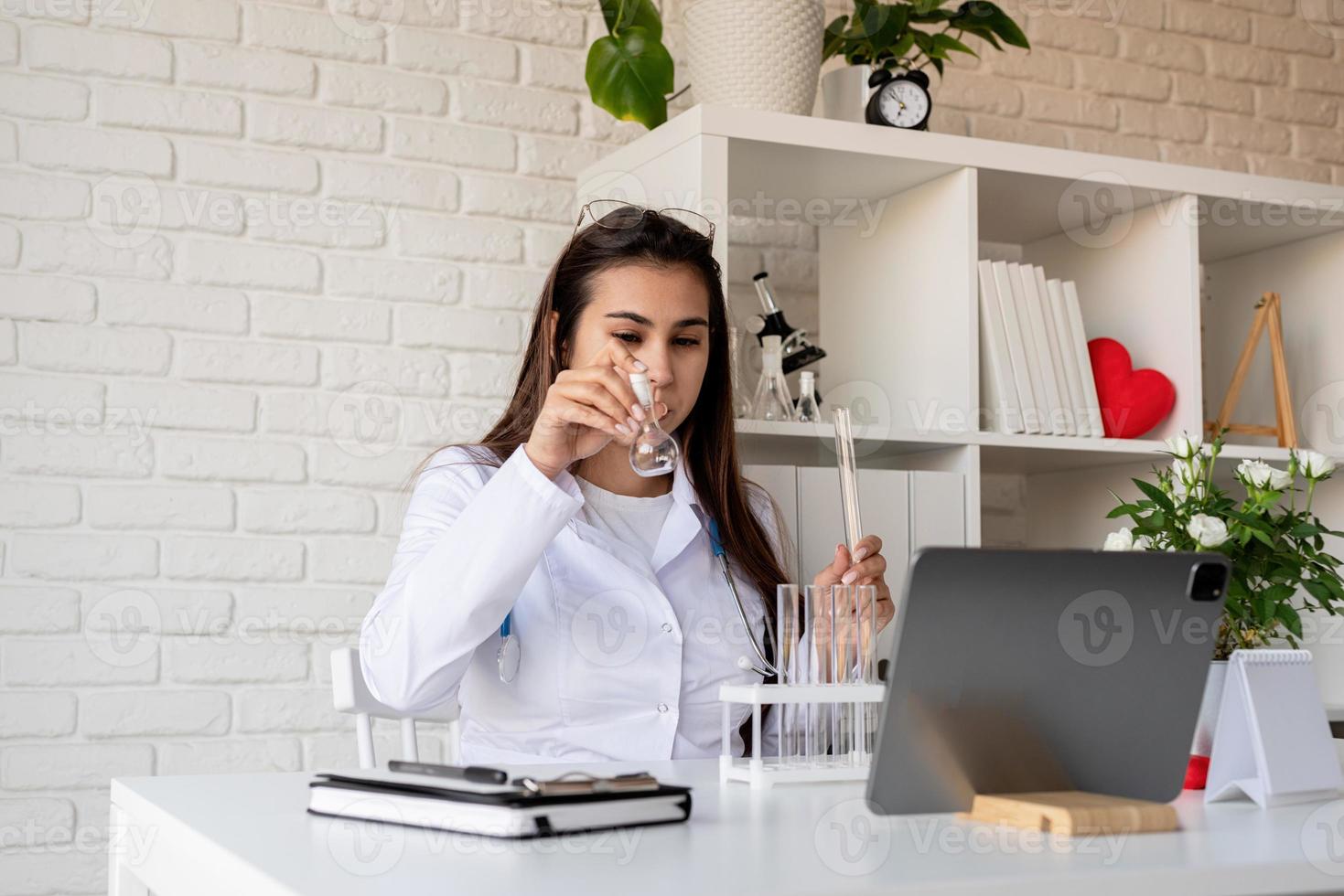 jovem médica fazendo uma chamada ou consultoria online, médico trabalhando online em casa foto