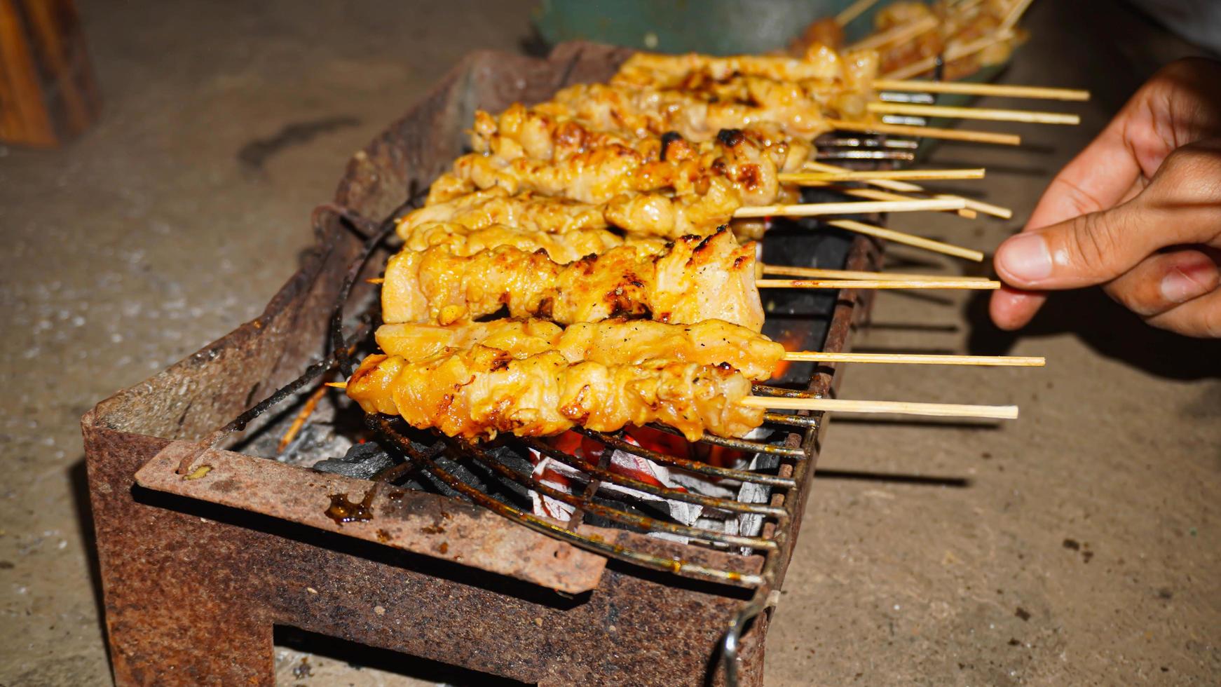 o processo de fazer comida satay, grelhada na brasa de carvão foto