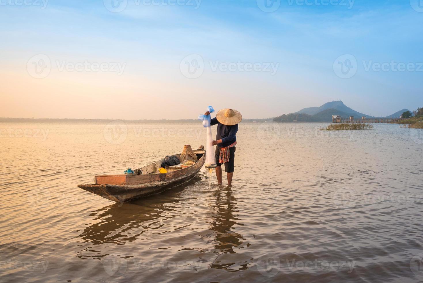 pescador asiático jogando uma rede para pegar peixes de água doce no rio da natureza no início da manhã, antes do nascer do sol foto