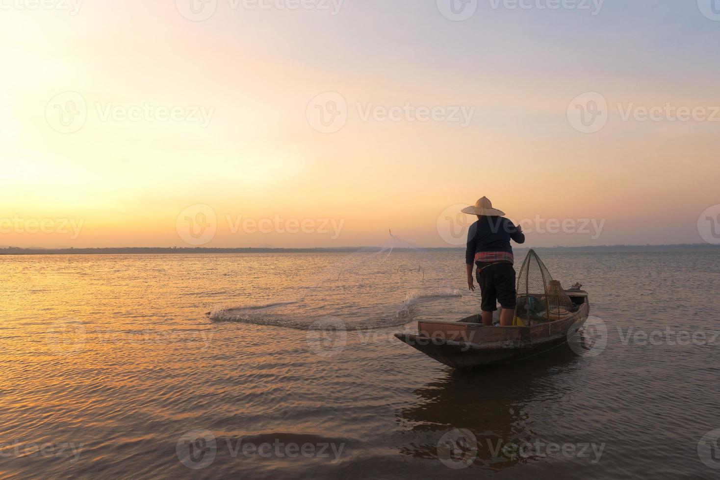 pescador asiático com seu barco de madeira indo para pegar peixes de água doce no rio da natureza no início durante o nascer do sol foto