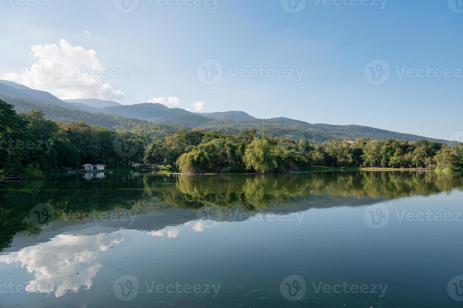 vista do reservatório de ang kaew com reflexo de montanha e céu azul em dia ensolarado foto