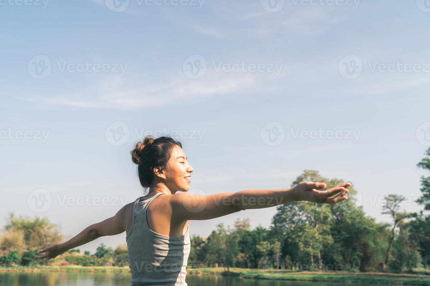 jovem mulher asiática ioga ao ar livre, mantenha a calma e medite enquanto pratica ioga para explorar a paz interior. ioga tem bons benefícios para a saúde perto do lago no parque. esporte e conceito de estilo de vida saudável. foto