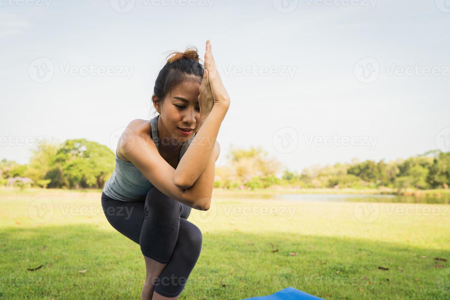 jovem mulher asiática ioga ao ar livre, mantenha a calma e medite enquanto pratica ioga para explorar a paz interior. ioga e meditação trazem bons benefícios para a saúde. esporte de ioga e conceito de estilo de vida saudável. foto