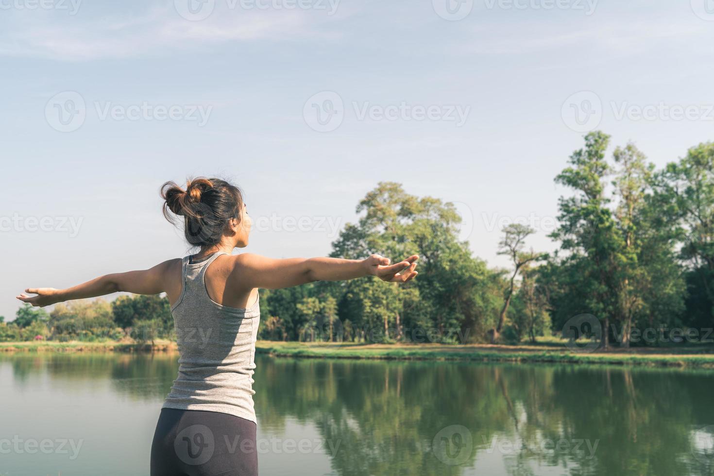 jovem mulher asiática ioga ao ar livre, mantenha a calma e medite enquanto pratica ioga para explorar a paz interior. ioga tem bons benefícios para a saúde perto do lago no parque. esporte e conceito de estilo de vida saudável. foto