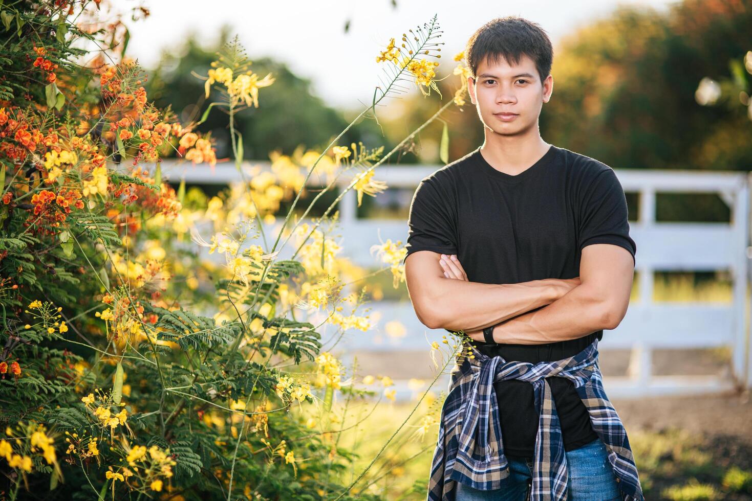 o viajante masculino veste uma camisa preta e está em um jardim de flores. foto