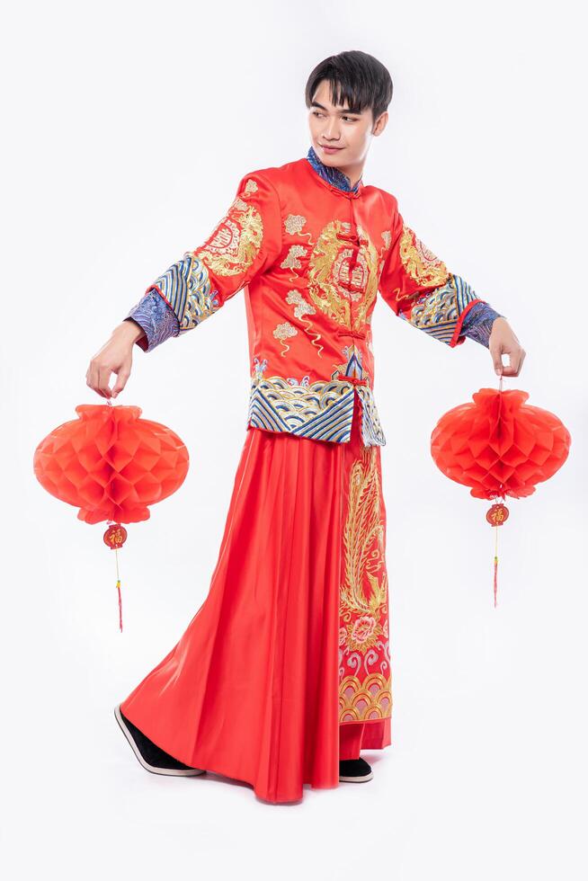 homem usa terno cheongsam mostra decoração de lâmpada vermelha em sua loja no ano novo chinês foto