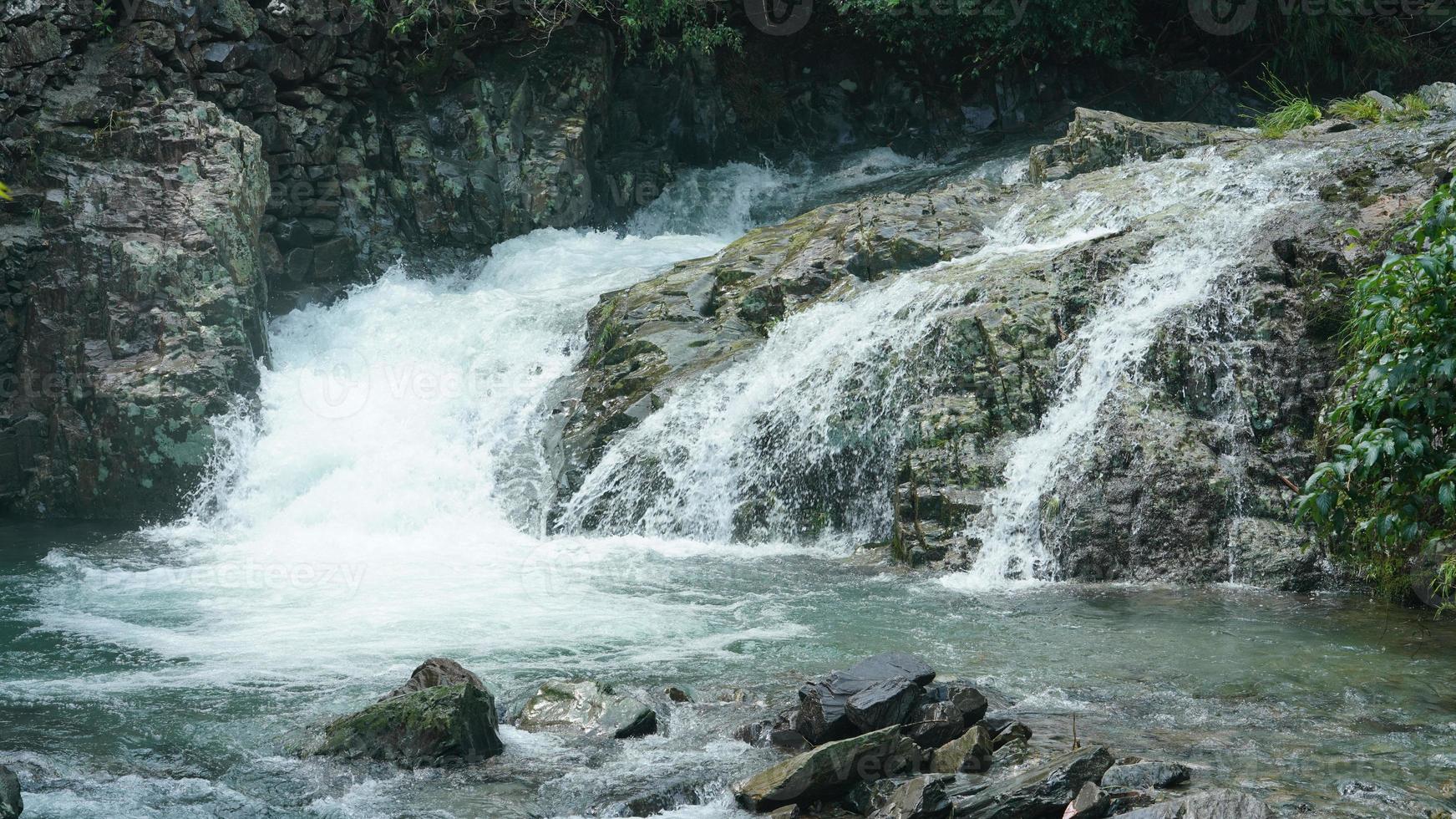 a bela vista do campo com a cachoeira fluindo nas montanhas após o dia chuvoso foto