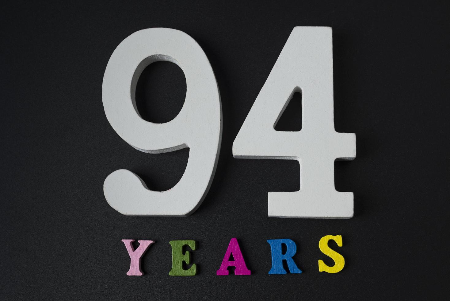 letras e números noventa e quatro anos em um fundo preto. foto