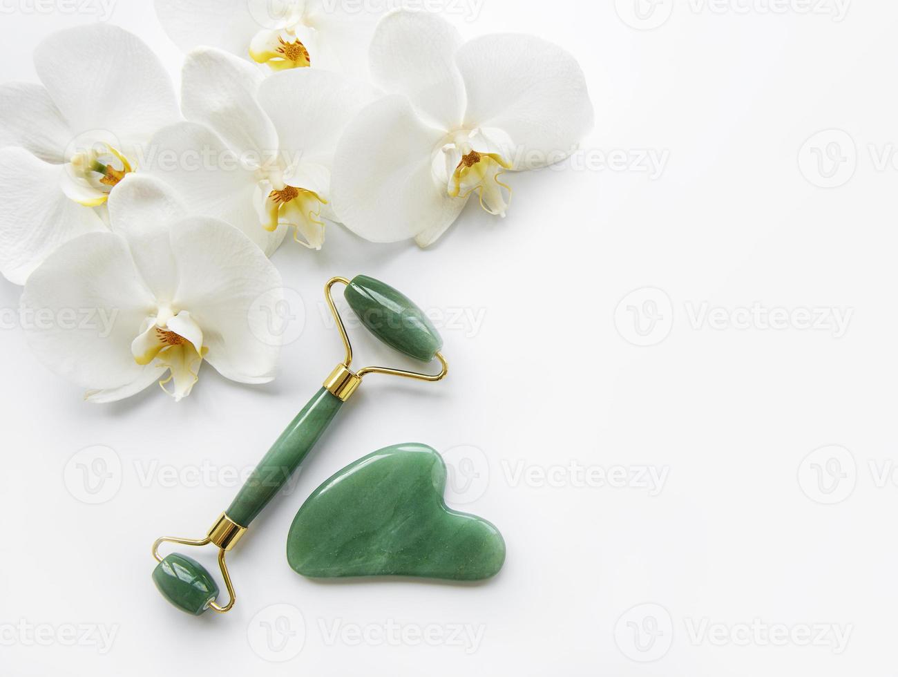 Rolos de jade para massagem facial em fundo branco foto