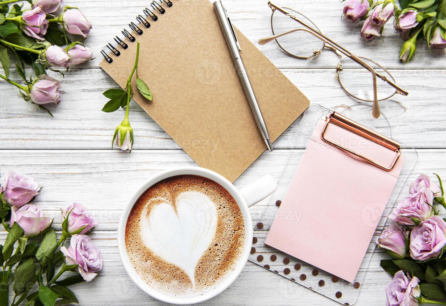 espaço de trabalho com diário, caderno, área de transferência, rosas sobre fundo branco. foto