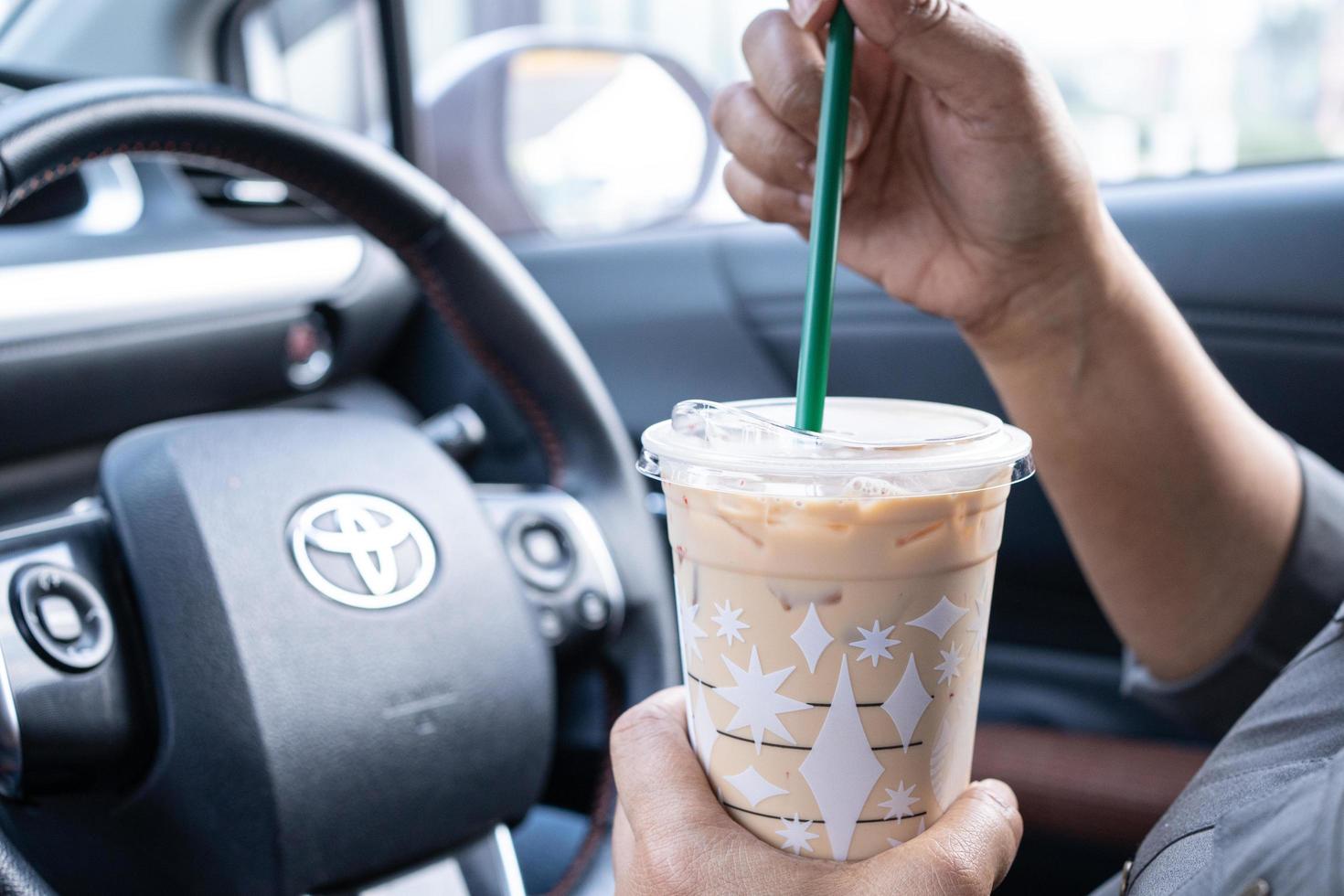 Bangkok, Tailândia - 1 de dezembro de 2021 Senhora asiática segurando café gelado no carro perigoso e risco de um acidente. foto