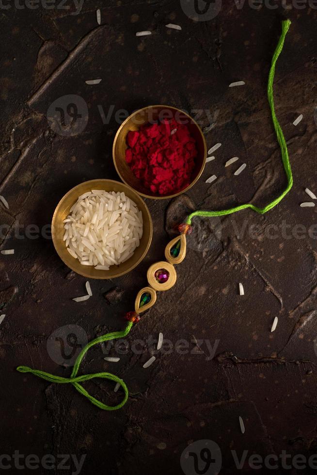 fundo raksha bandhan com um elegante rakhi, grãos de arroz e kumkum. uma pulseira tradicional indiana que é um símbolo de amor entre irmãos e irmãs. foto