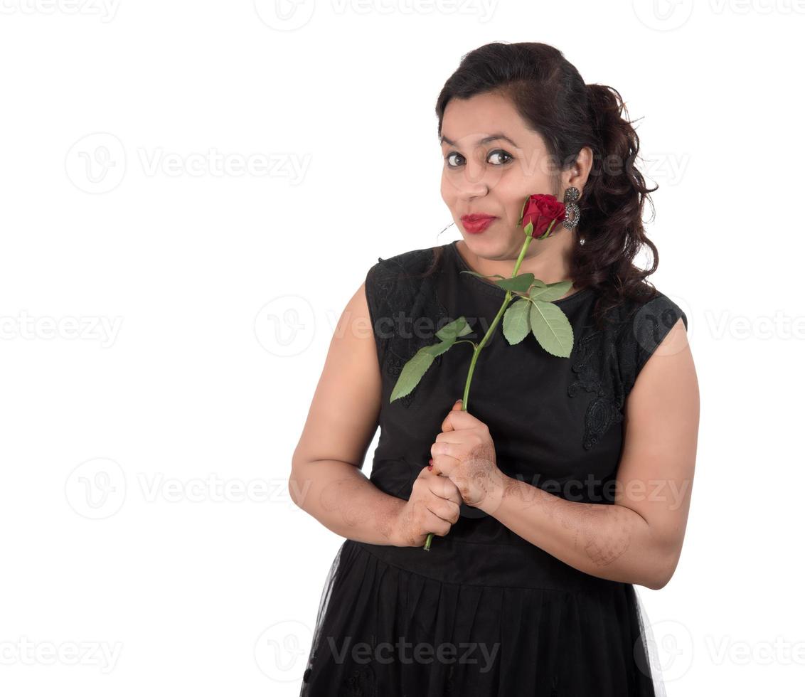 linda jovem ou mulher segurando e posando com uma flor rosa vermelha em fundo branco foto