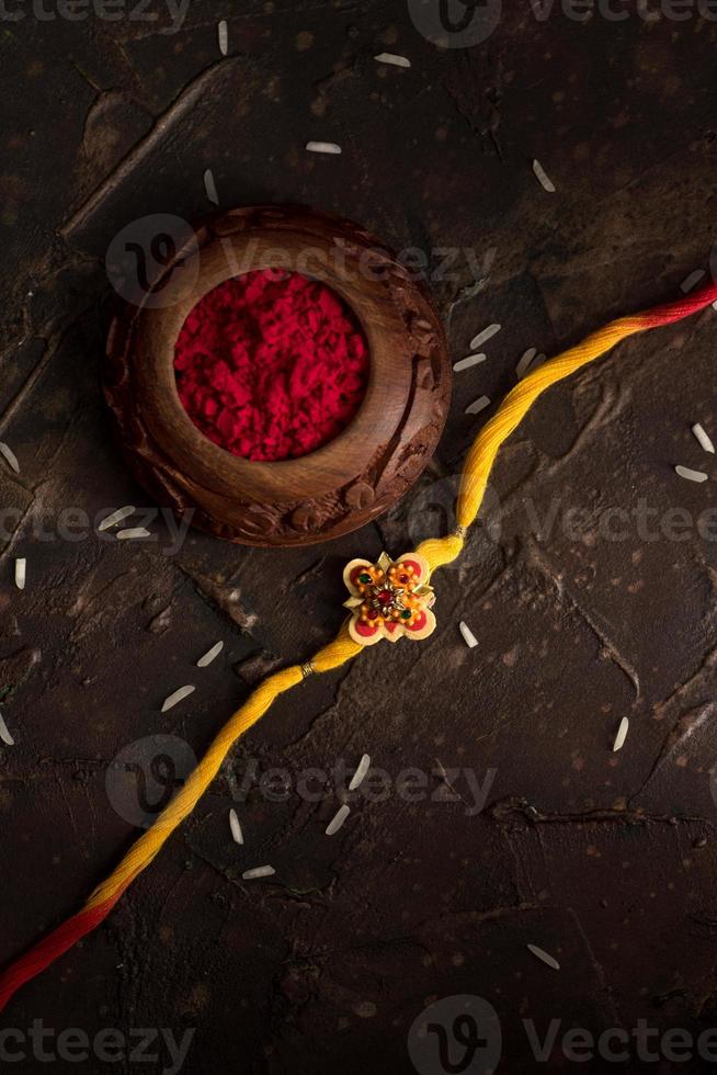 fundo raksha bandhan com um elegante rakhi, grãos de arroz e kumkum. uma pulseira tradicional indiana que é um símbolo de amor entre irmãos e irmãs. foto