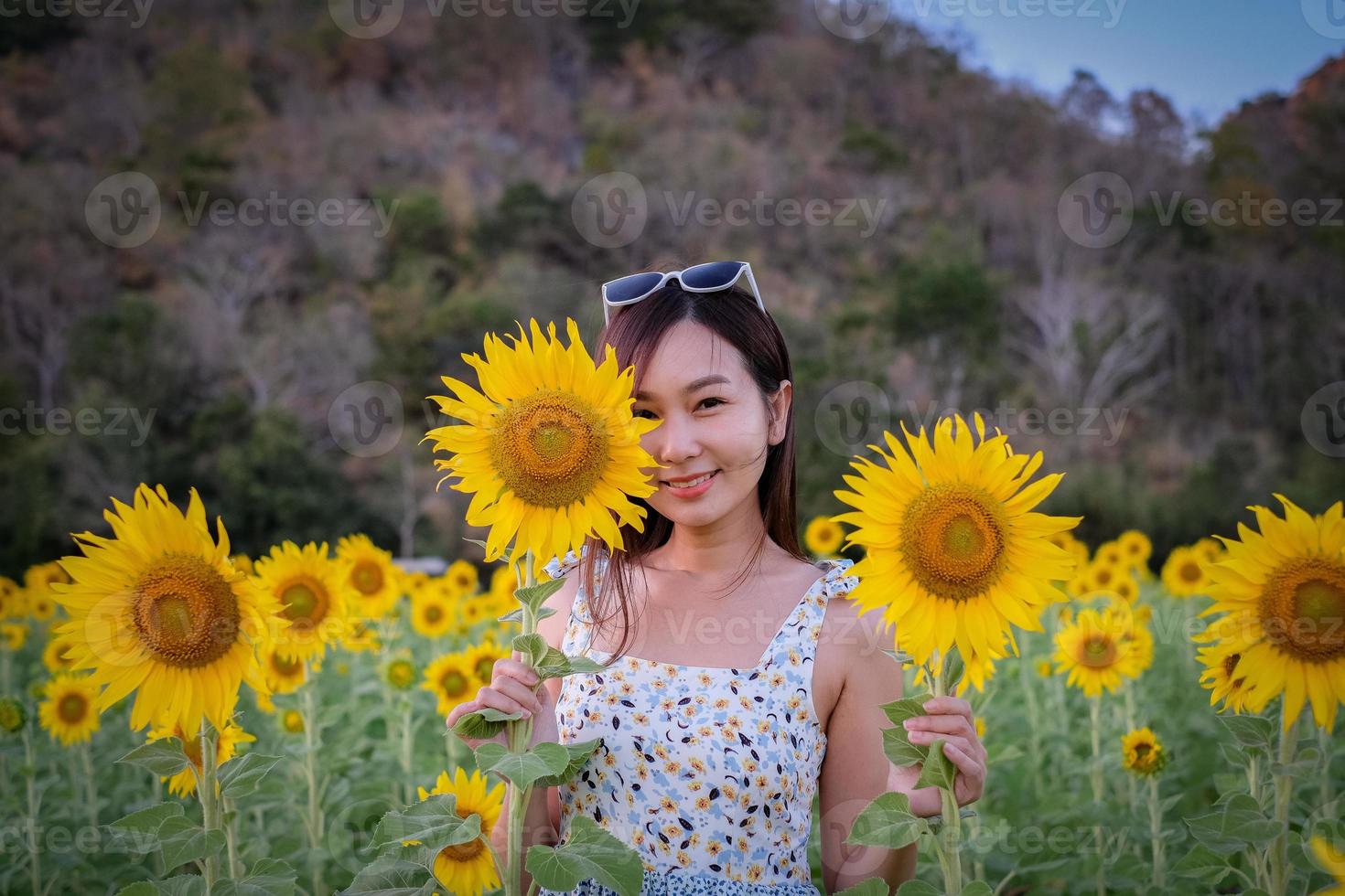 feliz alegre menina asiática com girassol, curtindo a natureza e sorrir no verão no campo de girassol. foto