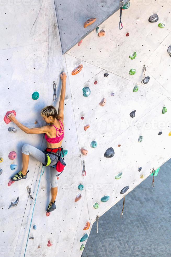 uma mulher está escalando uma parede de escalada foto