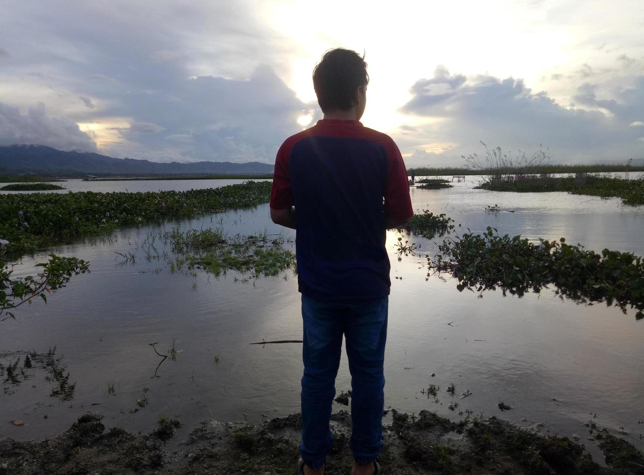 um jovem que aprecia a beleza do lago Limboto à tarde foto