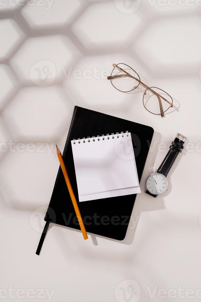 calendário em branco de estilo mínimo para mock up, caderno, óculos da moda, relógio e lápis no fundo branco foto