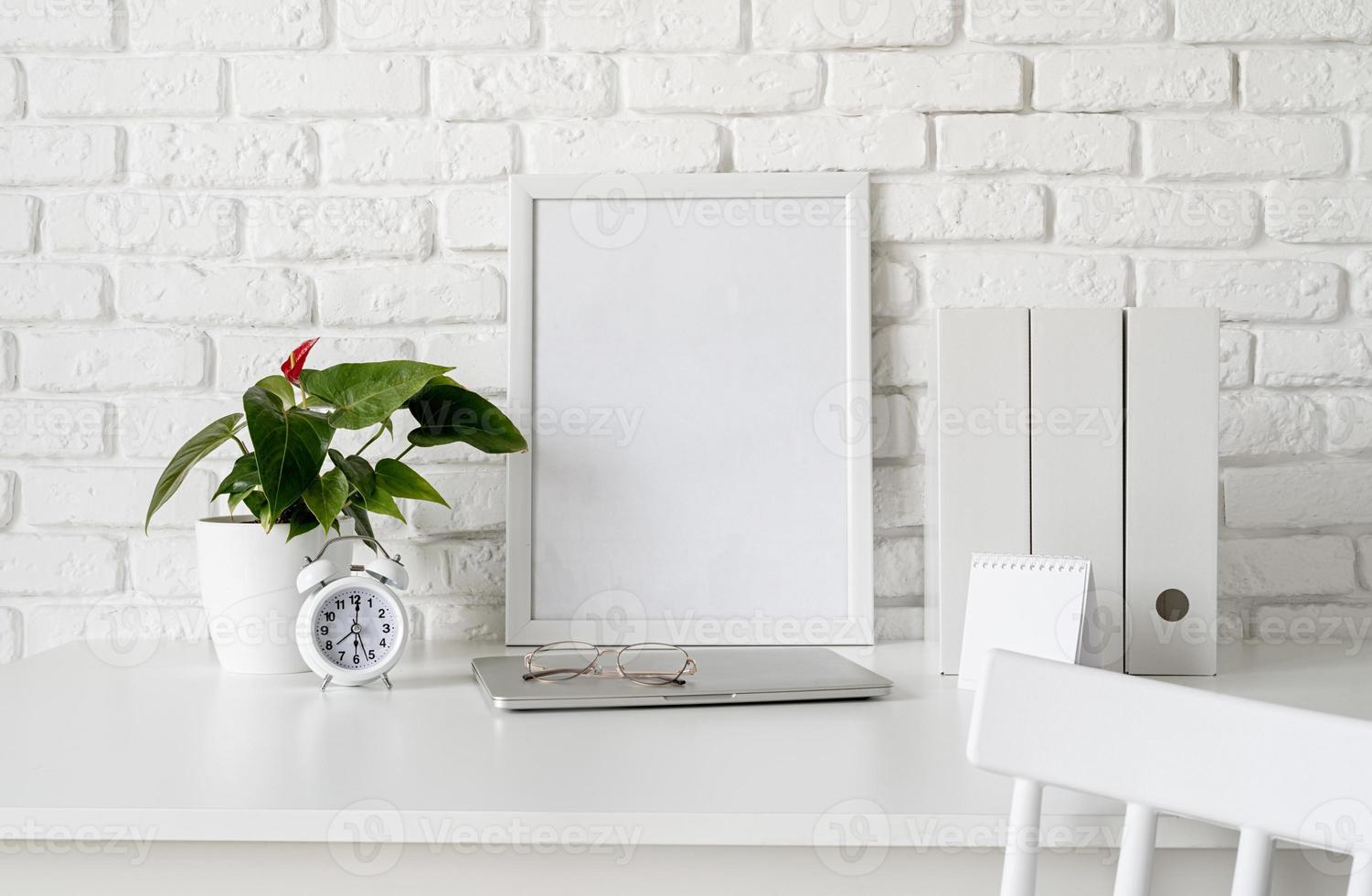 vista frontal da disposição da mesa com calendário em branco para simulação, pastas de papel e moldura branca com espaço de cópia foto