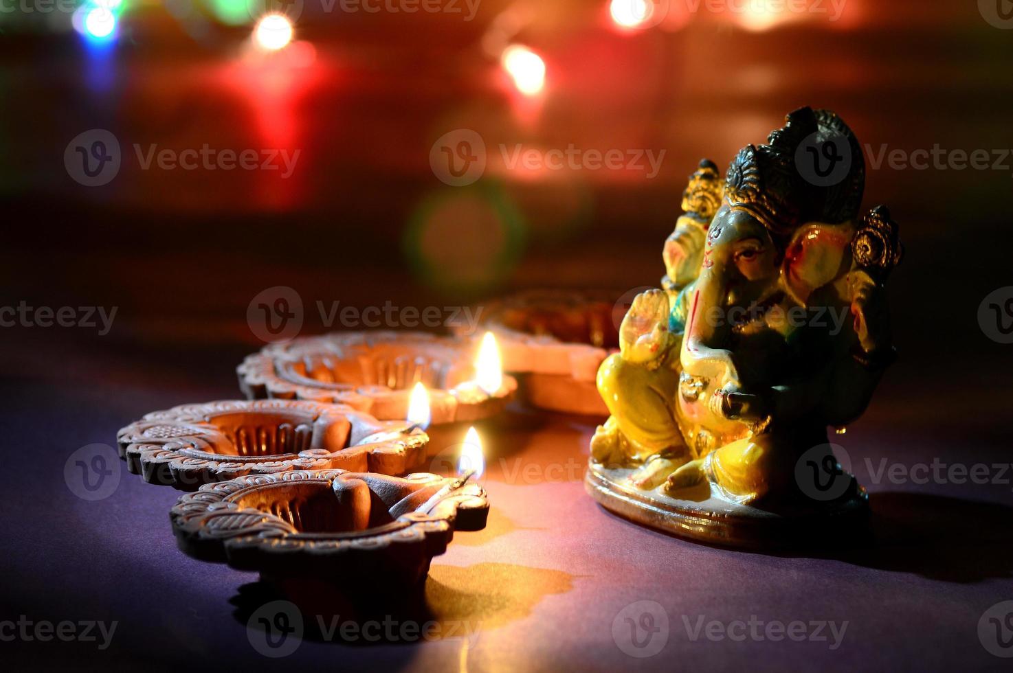 lâmpadas diya de argila acesas com o senhor ganesha durante a celebração do diwali. projeto de cartão de saudações festival indiano da luz hindu chamado diwali foto