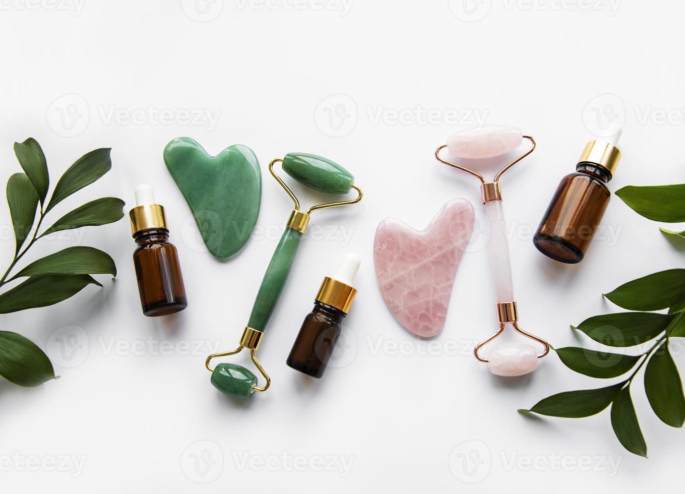 Rolos de jade para massagem facial em fundo branco foto